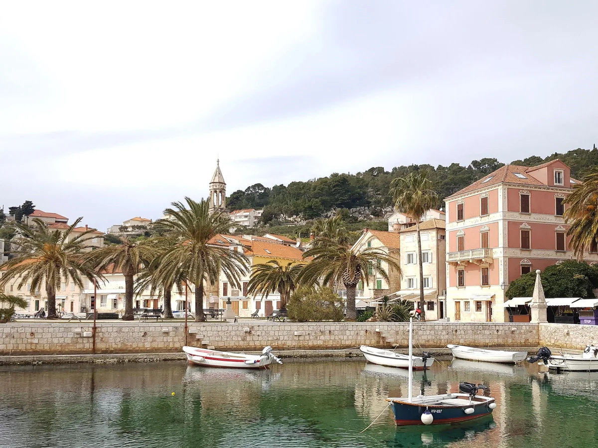 Hvar bys havnefront med palmer, små fortøjede både og historiske stenbygninger